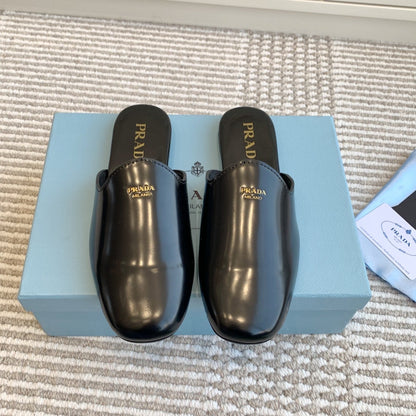 PRADA MULES IN BLACK GLOSSY SHEEPSKIN GOLD LETTERING LOGO