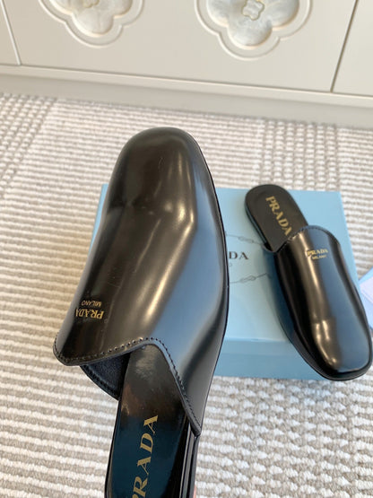 PRADA MULES IN BLACK GLOSSY SHEEPSKIN GOLD LETTERING LOGO