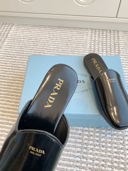 PRADA MULES IN BLACK GLOSSY SHEEPSKIN GOLD LETTERING LOGO